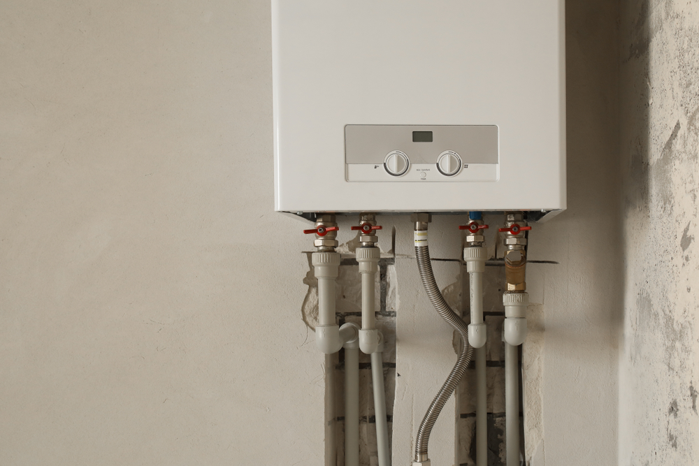 Wall-mounted electric hot water unit with valves and pipework installed by a Wagga Wagga electrician